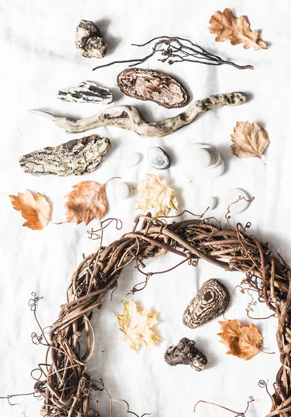 Natural nature objects for creative crafts - vine wreath, stones, leaves, wood on a light background, top view. Homemade creativity concept