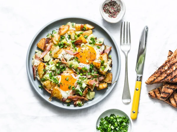 Potatoes, ham, eggs breakfast hash on a light background, top view. Delicious, nutritious breakfast, snack