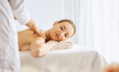 Güzel bir kadın kapalı gözlerle sırt masajından hoşlanıyor. Spa tedavisi kavramı