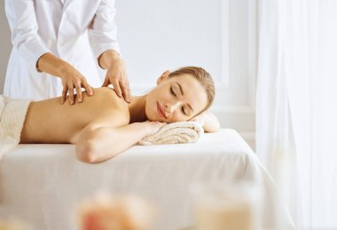 Güzel bir kadın kapalı gözlerle sırt masajından hoşlanıyor. Spa tedavisi kavramı