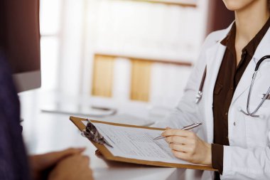 Doktor ve hasta güneşli klinikte otururken sağlık muayenesini tartışıyorlar. Hastanede mükemmel bir tıbbi hizmet.