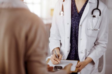 Doktor ve hasta güneşli klinikte otururken sağlık muayenesini tartışıyorlar. Hastanede mükemmel bir tıbbi hizmet.