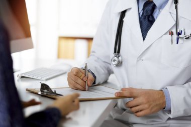 Dost canlısı kızıl sakallı doktor ve hasta kadın güneşli klinikte otururken sağlık muayenesini tartışıyorlar. Tıp konsepti