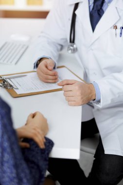 Dost canlısı kızıl sakallı doktor ve hasta kadın güneşli klinikte otururken sağlık muayenesini tartışıyorlar. Tıp konsepti