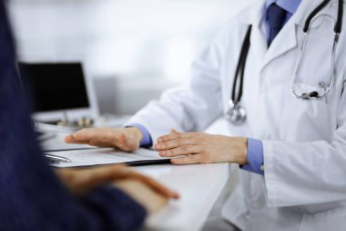 Bir doktor, hastanedeki dolapta birlikte otururken hastasıyla konuşuyor. Doktor ilaç kayıtlarını doldurmak için pano kullanıyor. Mükemmel tıbbi hizmet...