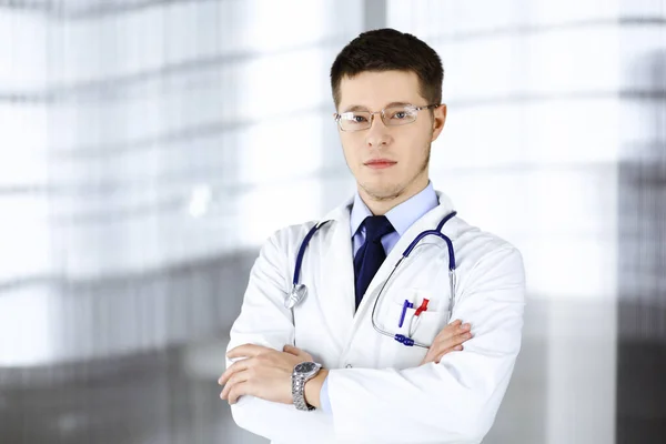 Dottore uomo, con occhiali e stetoscopio, è in piedi presso il suo ufficio in ospedale. Servizio medico perfetto in clinica. Buon futuro in medicina e sanità — Foto Stock