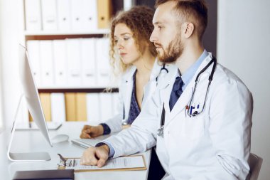 Kızıl sakallı doktor ve bayan meslektaşı güncel hastalık terapisini güneşli klinikte çalışırken tartışıyorlar. Tıpta takım çalışması