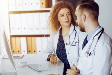 Kızıl sakallı doktor ve bayan meslektaşı güncel hastalık terapisini güneşli klinikte çalışırken tartışıyorlar. Tıpta takım çalışması