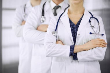Doktorlar klinikte kollarını kavuşturmuş bir takım gibi duruyorlar. Tıbbi yardım, sigorta ve tıp konsepti