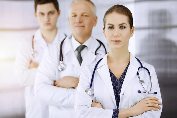 Doctors standing as a team with arms crossed in sunny clinic and ready to help patients. Medical help, insurance in health care, best disease treatment concept — Stock Photo, Image