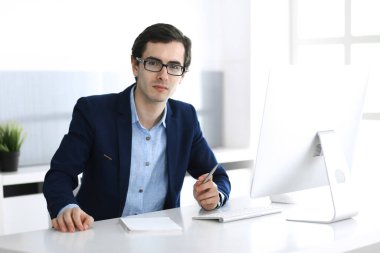 Modern ofiste bilgisayarla çalışan bir iş adamı. İş yerindeki erkek girişimcinin ya da şirket müdürünün vesikalığı. İş konsepti