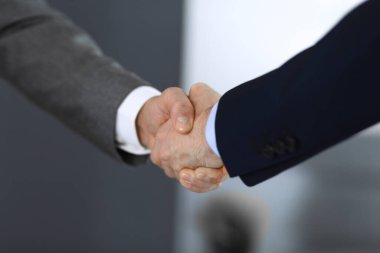 İş adamları toplantıdan ya da pazarlıktan sonra iş arkadaşlarıyla el sıkışıyorlar. Yakın plan. Modern ofisteki bir grup tanınmamış iş adamı ve kadın. Takım çalışması, ortaklık ve tokalaşma