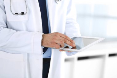 Doktor, ağ araştırması ya da sanal hastalık tedavisi için tablet bilgisayar kullanıyor. Eller yakın çekim. Klinikte mükemmel bir tıbbi hizmet. Modern tıp, tıbbi veri ve sağlık hizmetleri kavramları. Ayarlanmış
