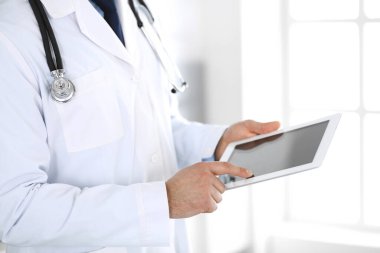 Doktor, ağ araştırması ya da sanal hastalık tedavisi için tablet bilgisayar kullanıyor. Eller yakın çekim. Klinikte mükemmel bir tıbbi hizmet. Modern tıp, tıbbi veri ve sağlık hizmetleri kavramları. Ayarlanmış