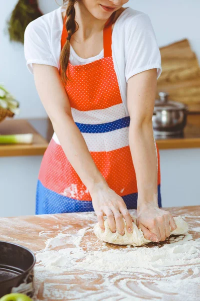 Mladá brunetka žena vařící pizzu nebo ručně dělané těstoviny v kuchyni. Hospodyně připravuje těsto na dřevěném stole. Dietní, stravovací a zdravotní koncepce — Stock fotografie