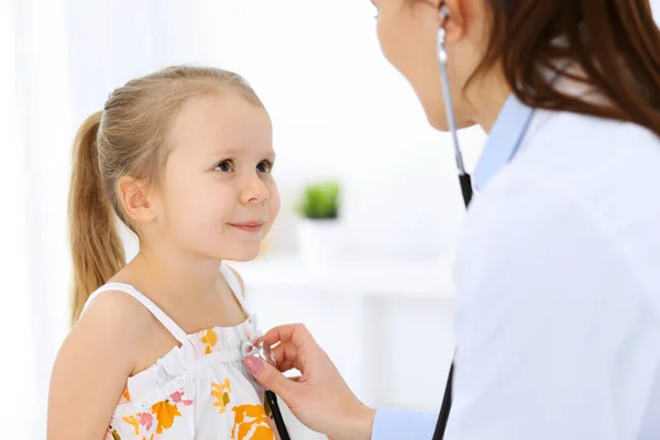 Doktorn undersöker en liten flicka med stetoskop. Glad leende barn patient vid vanlig läkarundersökning. Medicin och hälso- och sjukvård — Stockfoto