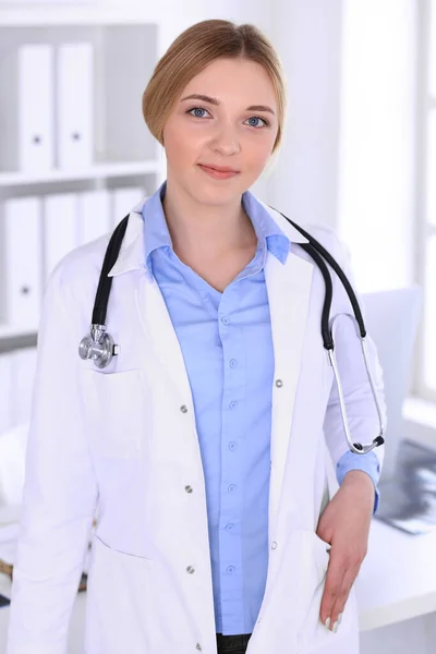 Junge Ärztin bei der Arbeit im Krankenhaus und blickt in die Kamera. Blaue Bluse des Therapeuten sieht gut aus. Medizin und Gesundheitskonzept — Stockfoto