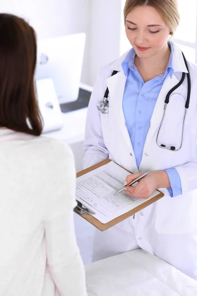 Junge Ärztin und Patientin bei der ärztlichen Untersuchung im Krankenhaus. Blaue Bluse des Therapeuten sieht gut aus. Medizin und Gesundheitskonzept — Stockfoto