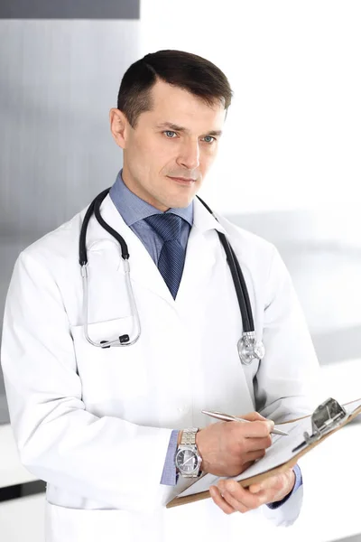 Doktorn använder urklipp för att fylla i journaler. Perfekt sjukvård på kliniken. Läkare på sjukhuset. Medicin och hälso- och sjukvård — Stockfoto