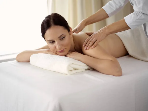 Ganska brunett kvinna njuter av proceduren med ryggmassage i spa salong. Skönhetsbegreppet — Stockfoto