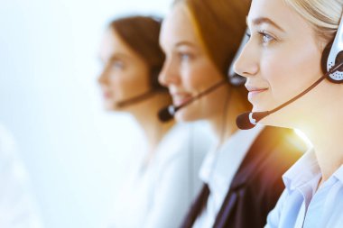 Güneşli ofiste çalışan bir grup farklı telefon operatörü. Kulaklıklı yakışıklı iş kadını müşterilere danışıyor. Çağrı merkezi ve iş adamları kavramı