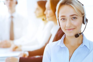 Güneşli ofiste çalışan bir grup farklı telefon operatörü. Kulaklıklı yakışıklı iş kadını müşterilere danışıyor. Çağrı merkezi ve iş adamları kavramı