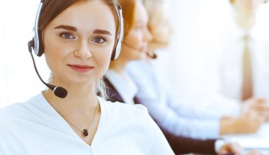 Güneşli ofiste çalışan bir grup farklı telefon operatörü. Kulaklıklı yakışıklı iş kadını müşterilere danışıyor. Çağrı merkezi ve iş adamları kavramı