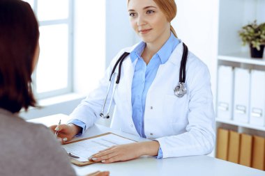 Hastane muayenehanesindeki genç kadın doktor ve hasta. Haki renkli terapist bluzu iyi görünüyor. Tıp, sağlık ve doktor randevu kavramı