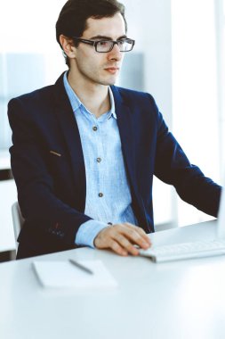 Modern ofiste bilgisayarla çalışan bir iş adamı. İş yerindeki erkek girişimcinin ya da şirket müdürünün vesikalığı. İş konsepti