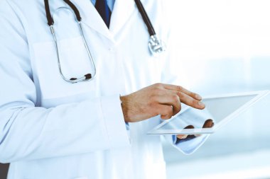 Doktor, ağ araştırması ya da sanal hastalık tedavisi için tablet bilgisayar kullanıyor. Eller yakın çekim. Klinikte mükemmel bir tıbbi hizmet. Modern tıp, tıbbi veri ve sağlık hizmetleri kavramları. Ayarlanmış