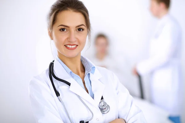 Vrouwelijke arts glimlachen op de achtergrond met patiënt in het bed en twee artsen — Stockfoto
