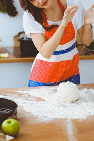 Genç esmer kadın mutfakta pizza ya da el yapımı makarna pişiriyor. Ev hanımı ahşap masada hamur hazırlıyor. Diyet, gıda ve sağlık konsepti — Stok fotoğraf