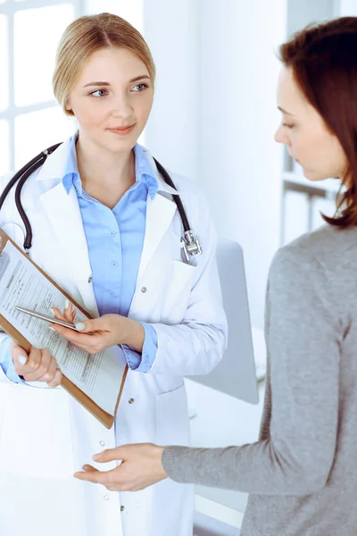 Молода жінка-лікар і пацієнт на медичному огляді в лікарняному кабінеті. Блузка синього кольору терапевта добре виглядає. Медицина та концепція охорони здоров'я — стокове фото