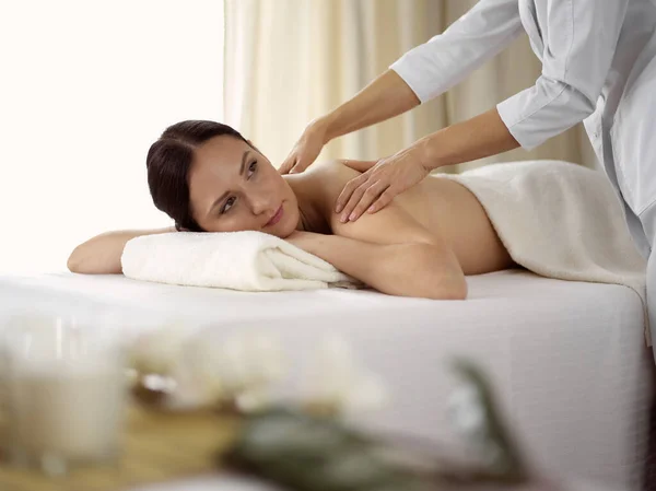 Ganska brunett kvinna njuter av proceduren med ryggmassage i spa salong. Skönhetsbegreppet — Stockfoto