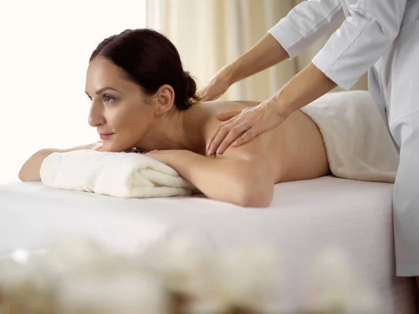 Pretty brunette woman enjoying procedure of back massage in spa salon. Beauty concept Stock Picture