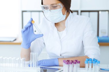Koruyucu gözlüklü profesyonel kadın bilim adamının laboratuarda reaktörlerle deney yapması. Tıp ve araştırma konsepti