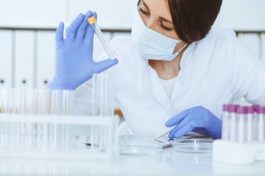 Koruyucu gözlüklü profesyonel kadın bilim adamının laboratuarda reaktörlerle deney yapması. Tıp ve araştırma konsepti