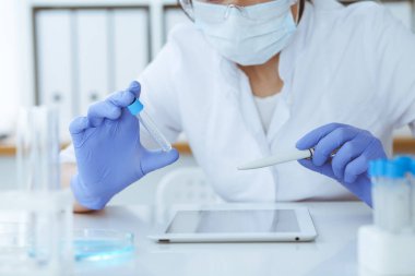 Koruyucu gözlüklü profesyonel kadın bilim adamının laboratuarda reaktörlerle deney yapması. Tıp ve araştırma konsepti