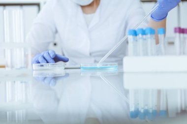 Koruyucu gözlüklü profesyonel kadın bilim adamının laboratuarda reaktörlerle deney yapması. Tıp ve araştırma konsepti