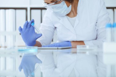 Koruyucu gözlüklü profesyonel kadın bilim adamının laboratuarda reaktörlerle deney yapması. Tıp ve araştırma konsepti