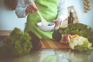 Mutfakta pişen bilinmeyen insan elleri. Kadın sebze salatasıyla meşgul. Sağlıklı yemek ve vejetaryen gıda konsepti.