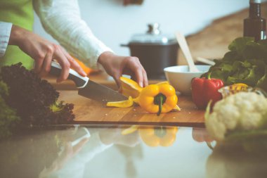 Mutfakta pişen bilinmeyen insan elleri. Sarı dolma biber dilimleyen kadın. Sağlıklı yemek ve vejetaryen gıda konsepti.