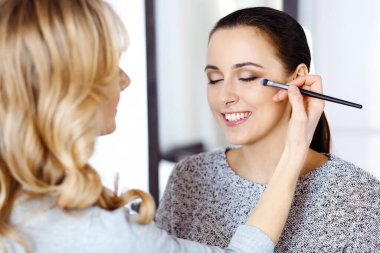 Profesyonel makyöz güzel genç bir kadınla çalışıyor. Gelin, moda ya da çıplak stil