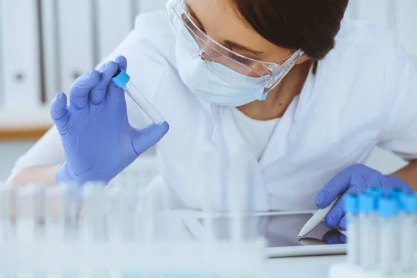 Close-up de cientista profissional feminino em óculos de proteção fazendo experiência com reagentes em laboratório. Medicina e conceito de pesquisa — Fotografia de Stock