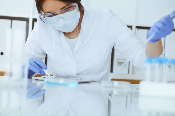 在实验室用试剂进行防护眼镜实验的专业女科学家的特写镜头。医学和研究概念 — 图库照片