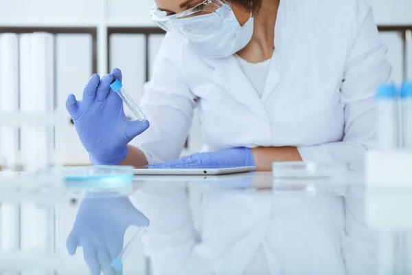 Primer plano de la científica profesional en gafas protectoras haciendo experimento con reactivos en laboratorio. Concepto de medicina e investigación — Foto de Stock