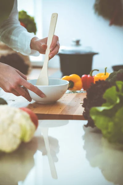 Neznámé lidské ruce vaří v kuchyni. Žena je zaneprázdněná zeleninovým salátem. Zdravé jídlo a koncepce vegetariánských potravin — Stock fotografie