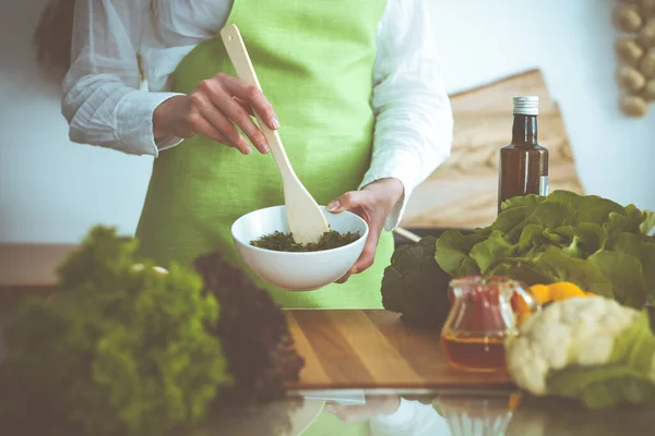 Neznámé lidské ruce vaří v kuchyni. Žena je zaneprázdněná zeleninovým salátem. Zdravé jídlo a koncepce vegetariánských potravin — Stock fotografie