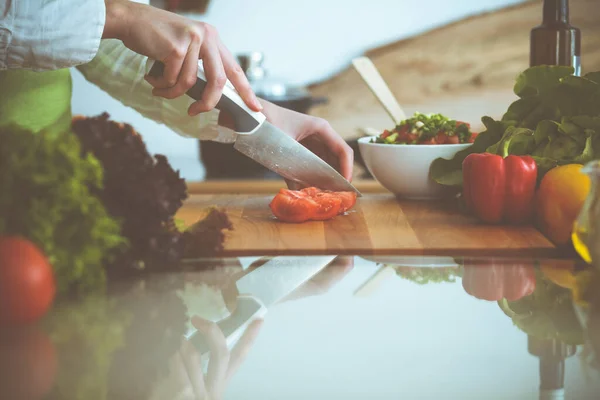 Manos humanas desconocidas cocinando en la cocina. Mujer cortando tomates rojos. Comida saludable y concepto de comida vegetariana —  Fotos de Stock