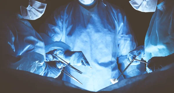 Group of surgeons wearing safety masks performing operation. Medicine concept — Stock Photo, Image